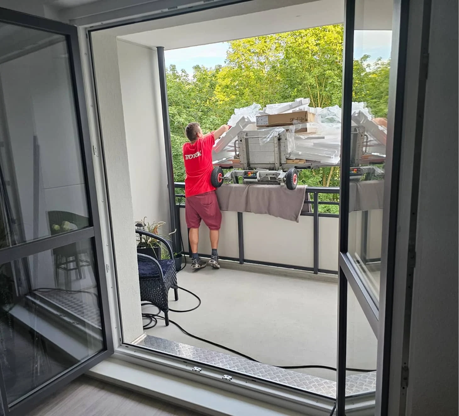 Bork-Mitarbeiter empfängt Möbellift-Plattform mit Umzugsgut auf einem Balkon