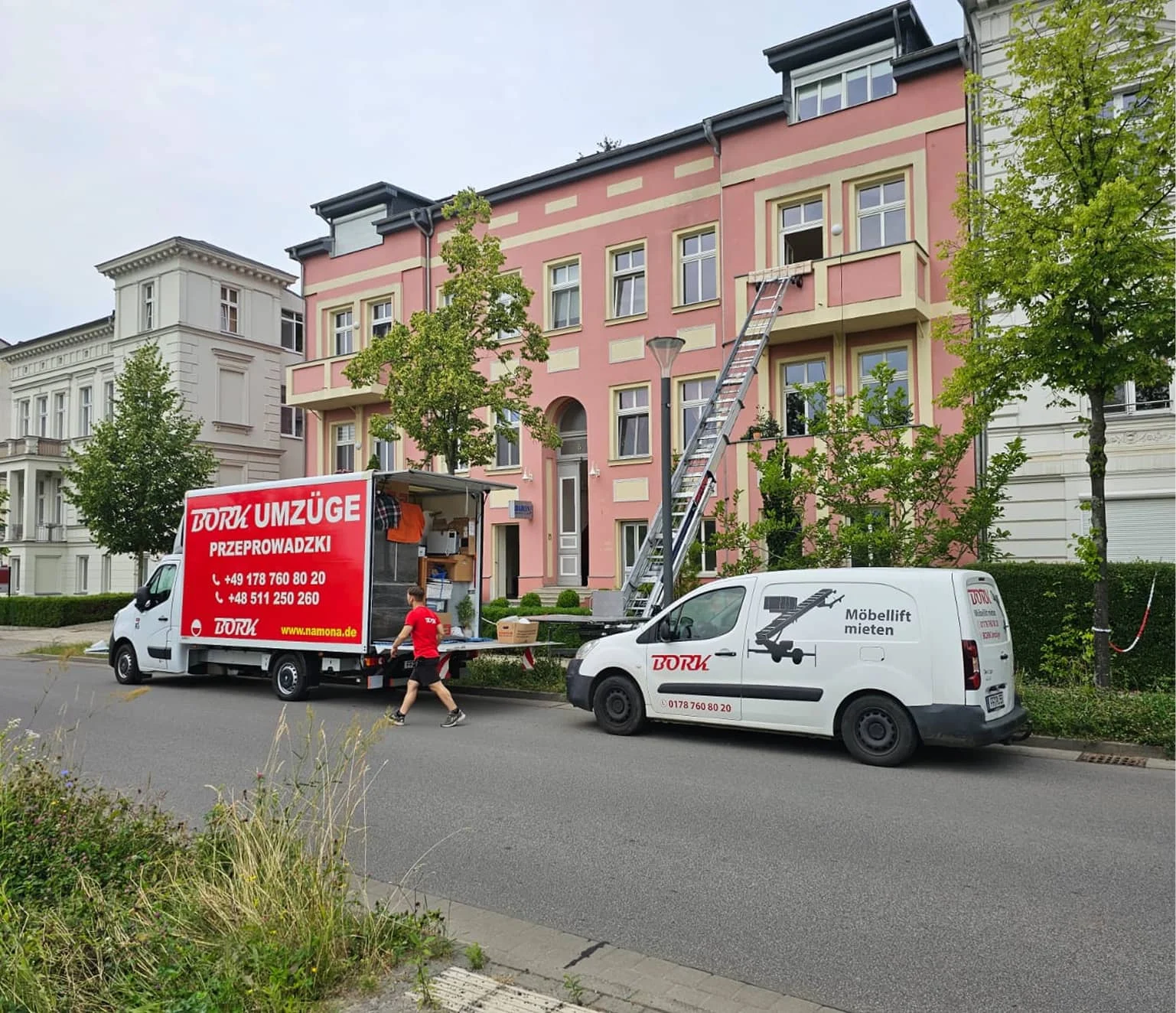 Bork Umzüge LKW und weißer Bork-Transporter „Möbellift mieten" vor rosa Gründerzeitgebäude