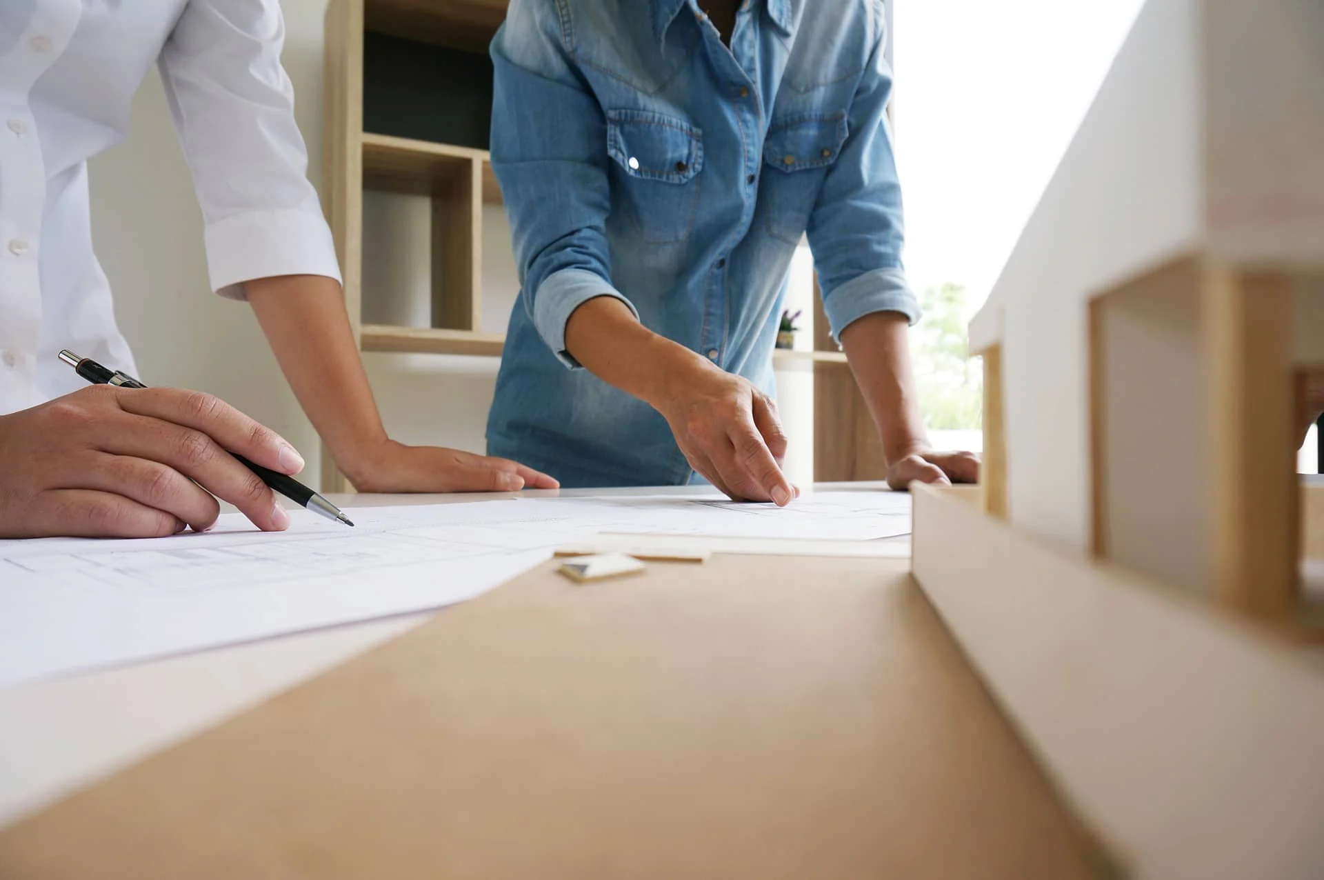 Zwei Personen planen gemeinsam einen Umzug anhand von Grundrisszeichnungen auf einem Tisch